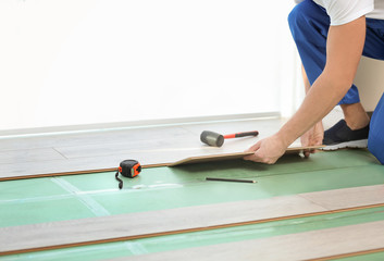 Male worker hands installing laminate flooring