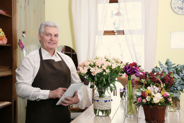 Male florist with tablet at flower shop