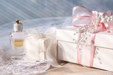 Wonderful composition of gift boxes, perfume and bridal veil on light background