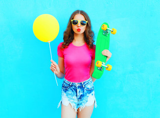 Fashion pretty woman and yellow air balloon with skateboard over colorful blue background
