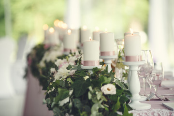 Table served for dinner in living room, close up view. Candles and goblets on a decorated wedding table.
