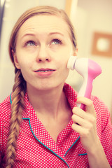 Woman using facial cleansing brush on face