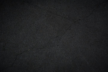 Schwarze dunkel porös strukturierte Steinwand mit einem grossen Riss als Hintergrund