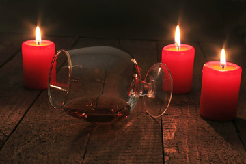 Glass of brandy or cognac and candle on the wooden table. Celebration composition.