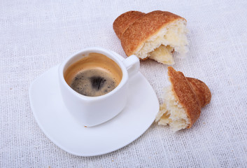 Crispy fresh croissants and cup of coffee espresso on a white background, morning breakfast, selective focus