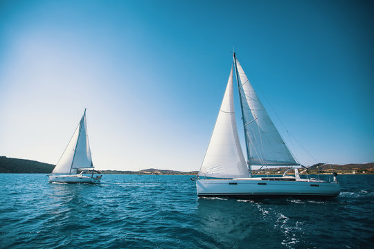 Sailing ship yachts with white sails in the sea.
