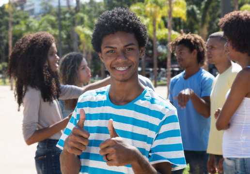 Young latin american man with braces showing thumb up