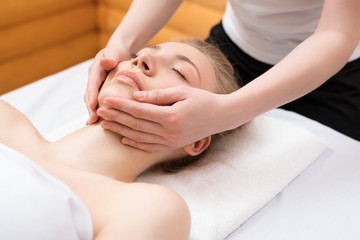 Young pretty woman enjoying face massage procedure