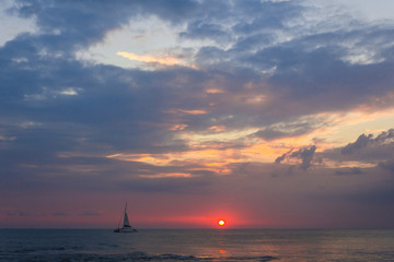 Naklejka na ściany i meble The boat sailing in sunset. A yacht sailing in sunset lights. Horizontal outdoors shot.