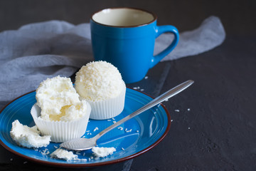 Small meringue cakes Pavlova with glaze and coconut On a blue plate. Selective focus with copy space