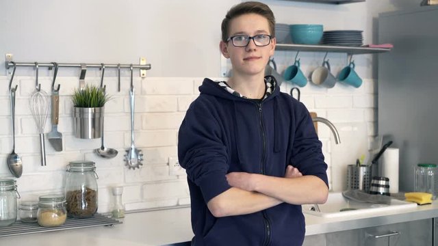 Portrait of happy, young boy standing in kitchen at home
