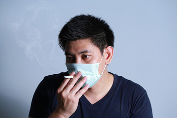 Stop smoking concept young man smoking cigarette with 
protective mask