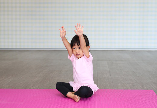 Little cute baby girl doing yoga exercise on the grass at