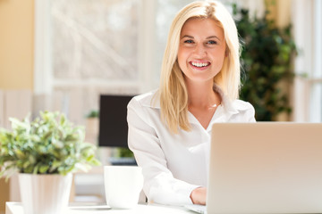 Happy young woman sitting at her desk