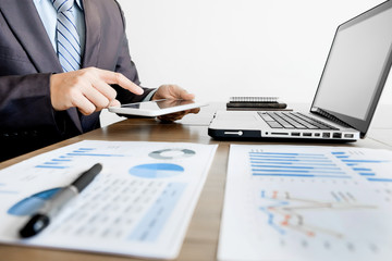 Multitasking. Handsome young man working with touchpad while sitting on the couch in office and financial statistic graph