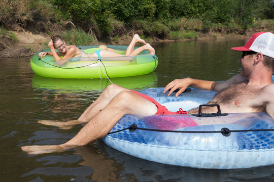 Couple Tubing Down The River In The Summer
