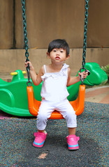 Cute child girl fun on a swing in playground