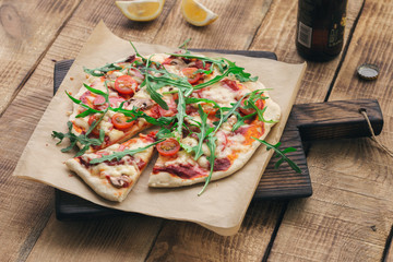 Pizza with cheese, sausage salami, mushrooms, tomatoes and arugula