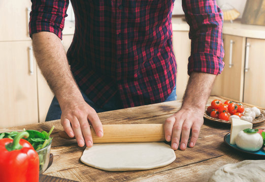 Man rolls out the dough for making homemade pizza