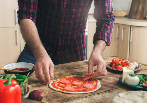 Man prepares homemade pizza on a wooden table