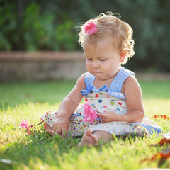 Portrait of cute happy baby girl on green glade, summer, park