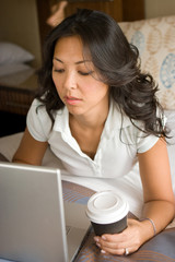 Woman Relaxing On Bed Using Laptop Computer