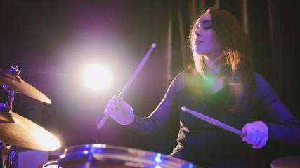 Fototapeta na wymiar Rock band rehearsing in the garage - attractive girl percussion drummer perform music break down