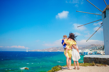 Happy family in front of windmills at popular tourist area on Mykonos island, Greece