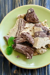 Tahini halva with chocolate and mint on green plate close-up.