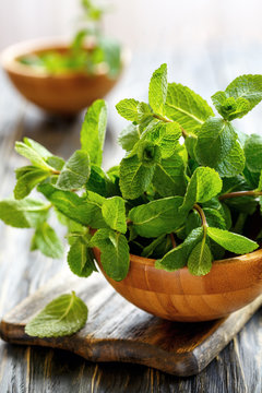 Fresh mint in a wooden bowl on the old board.