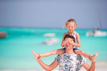 Happy father and his little daughter at tropical beach having fun