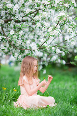 Adorable little girl enjoying spring day in apple blooming garden