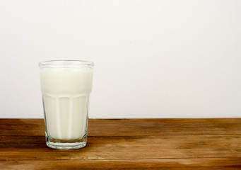A glass of milk over white background on a wooden surface