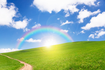 Naklejka premium idyllic landscape of green heels, blue sky, rainbow and sun