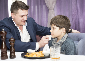 Father and son eat fried potatoes in a restaurant 