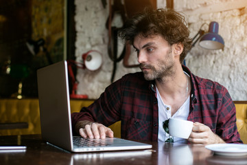 young man with laptop in front in a pub