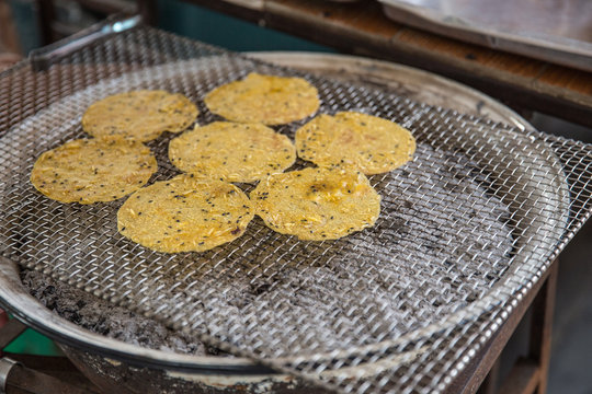 Thai traditional sesame dough sheet grill snack with old charcoal toaster.