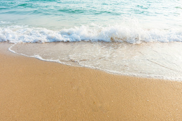 Soft wave of blue ocean on sandy beach at sunny day. Background subject is soft focus