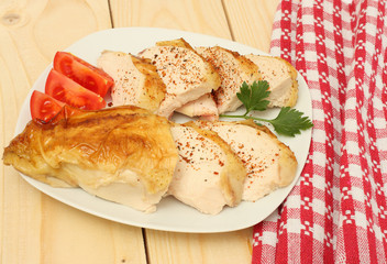 Grilled chicken fillet with tomato on wood background