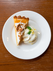 A piece of orange tart on a white plate decorated with whipped cream - 140596599
