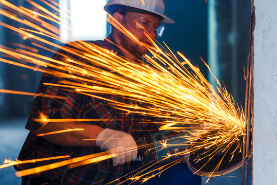 A construction worker using angle grinder. Sparks while grinding iron