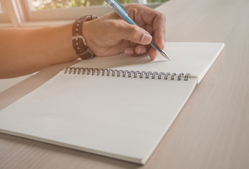 Man hand with pen writing on notebook.