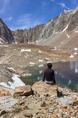 Female hiker observes the spectacular color of Lac Mort, Valpelline, Aosta valley, Italy