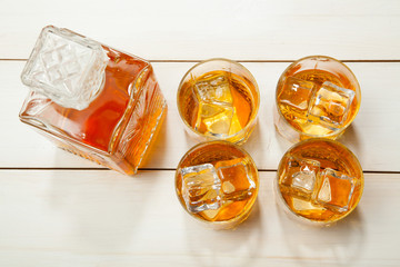 whiskey glass with ice and a decanter on  white wooden background