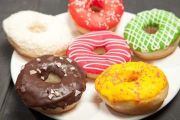 Colorful donuts on a black wooden background