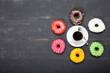 Cup with coffee and donuts on a black wooden table