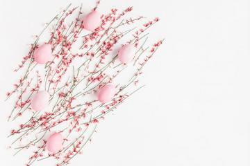 Easter eggs and pink flowers on white background. Easter, spring concept. Flat lay, top view