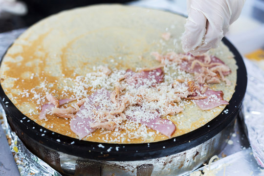Vendor making crepe with ham outdoors