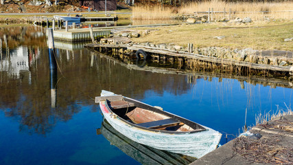 Fototapeta na wymiar Small traditional hunting canoe tied to a pier in calm and tranquil water. Location Blekinge archipelago in Sweden.