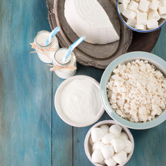 tasty healthy dairy products on a table on a blue background: sour cream, cottage cheese, mozzarella cheese, butter,ricotta and milk in a bottle